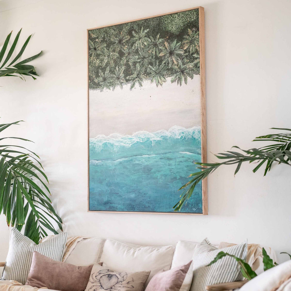 The Path Between – angled view of coastal artwork in oak frame showing top-down beach, palms and ocean wave | Original Artwork
