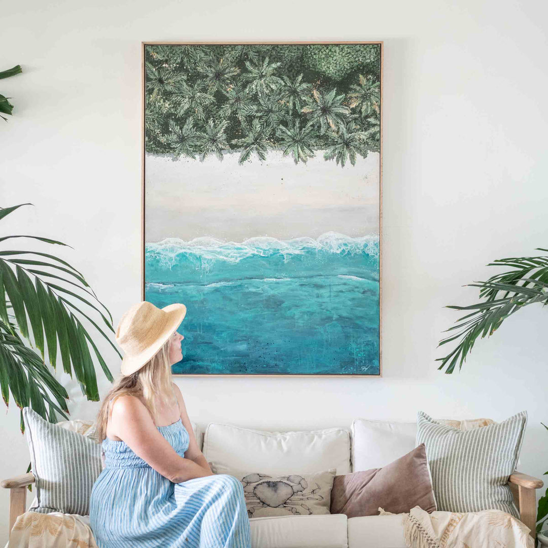 The Path Between – coastal artwork featuring top-down palm-lined beach and ocean with artist seated in tropical interior setting | Original Artwork