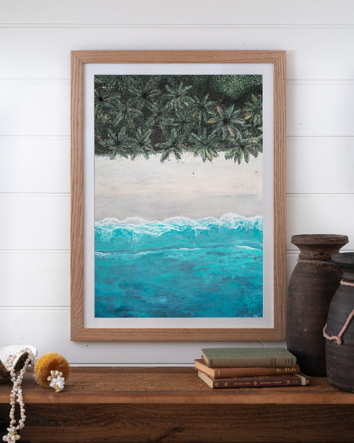 The Path Between – aerial beach and palm landscape, framed paper print in oak frame, styled on a timber shelf