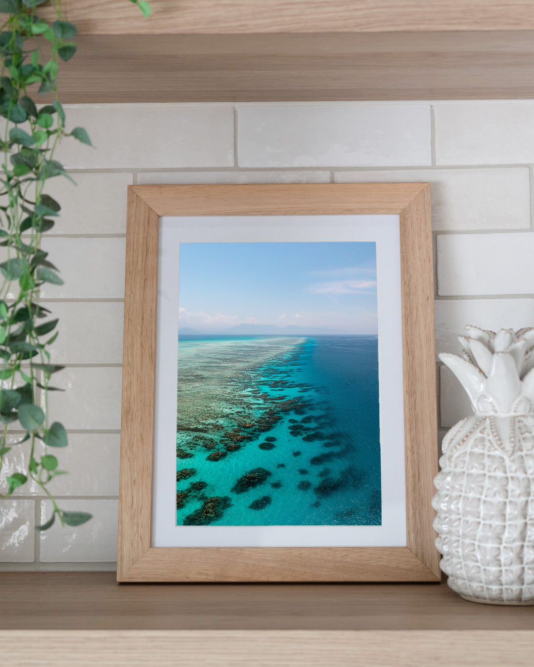 Tip of the Tongue – Tongue Reef, Aerial Photography by David Lloyd, framed paper print in oak frame, styled in a kitchen shelf setting
