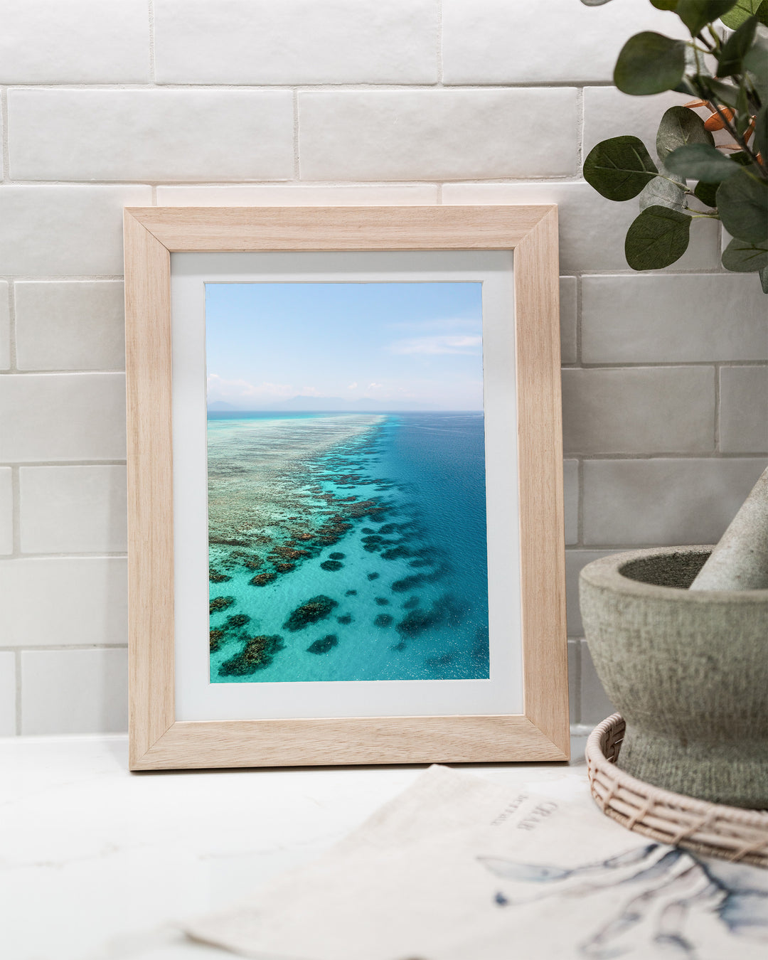Tip of the Tongue – Tongue Reef, Aerial Photography by David Lloyd, framed paper print in oak frame, styled in a kitchen bench setting