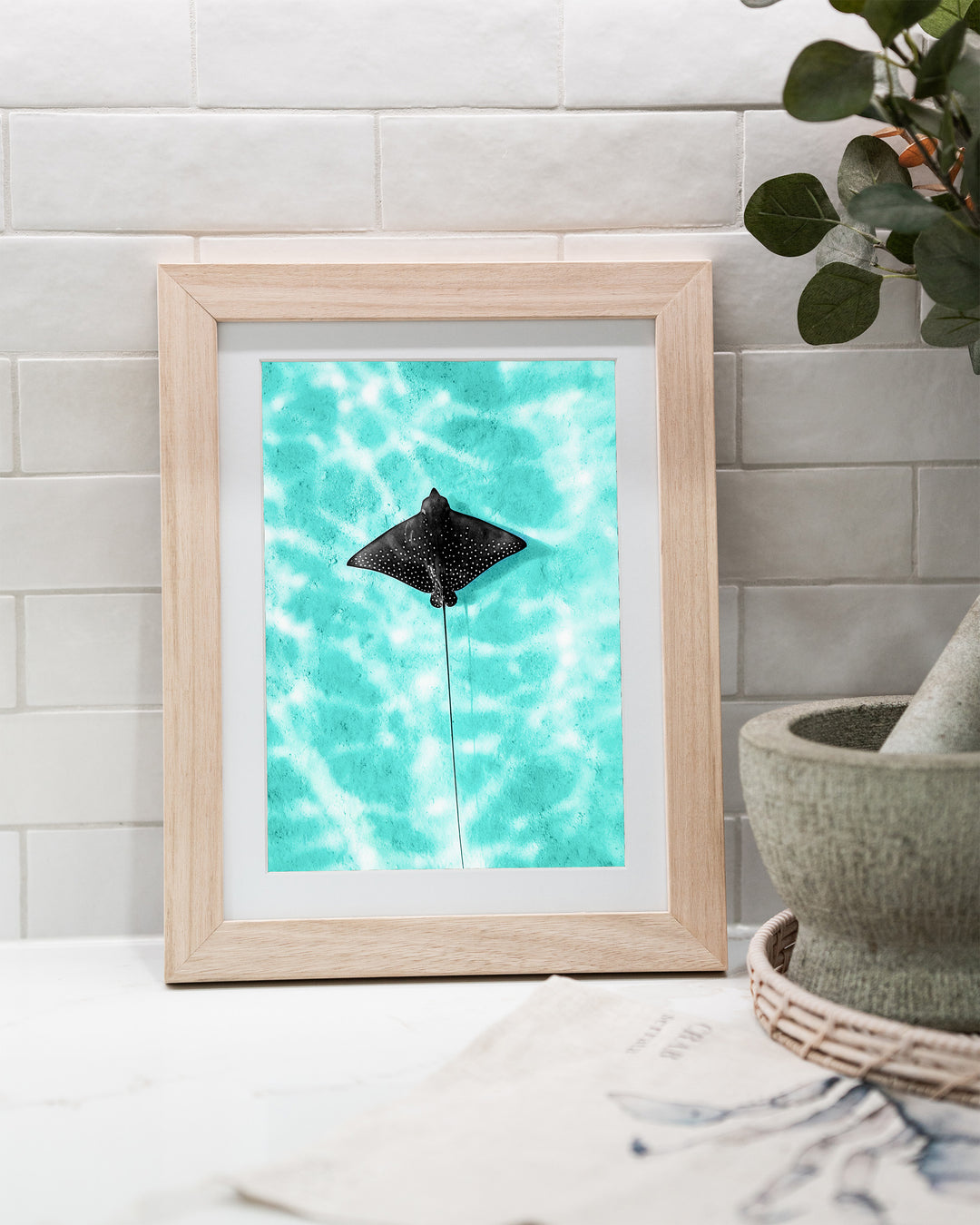 Turquoise Tranquility – Eagle Ray, Underwater Photography by David Lloyd, framed paper print in oak frame, styled in a kitchen bench setting
