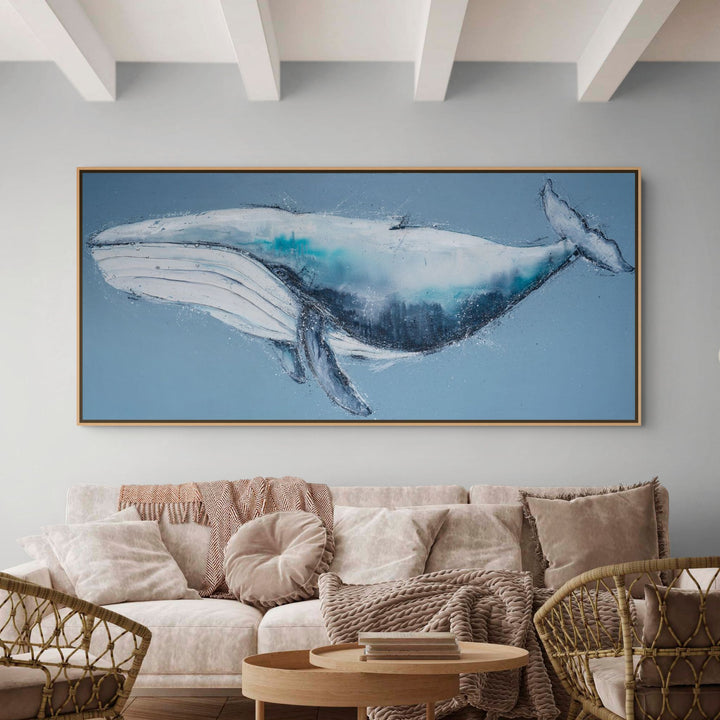 View from the Big Blue by Stephanie Elizabeth—a large acrylic whale hangs above a beige sofa in a modern living room.