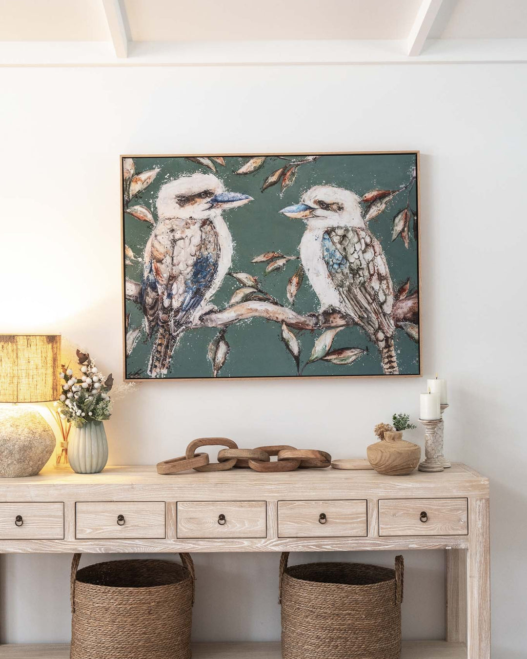 Wood console table with baskets, decor accents, lamp, and “We Belong Together” kookaburra print hanging above.