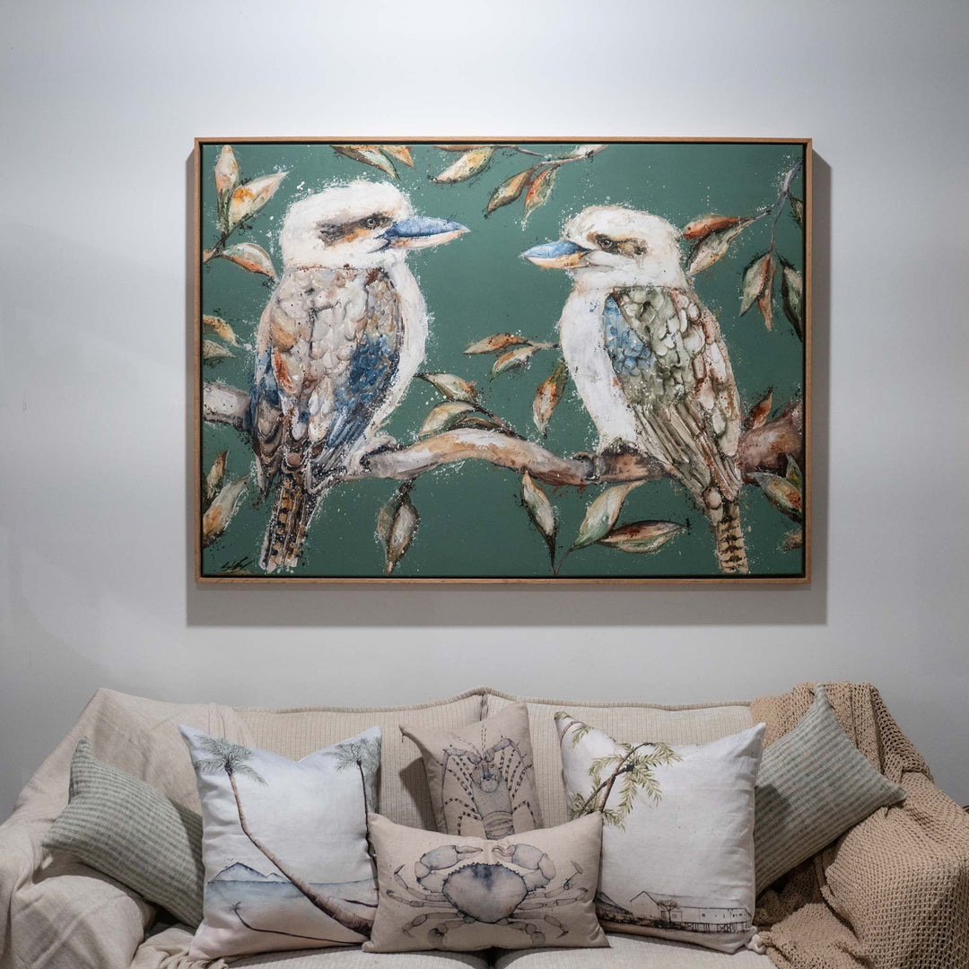We Belong Together artwork hangs above a beige couch decorated with bird and shell patterned pillows.