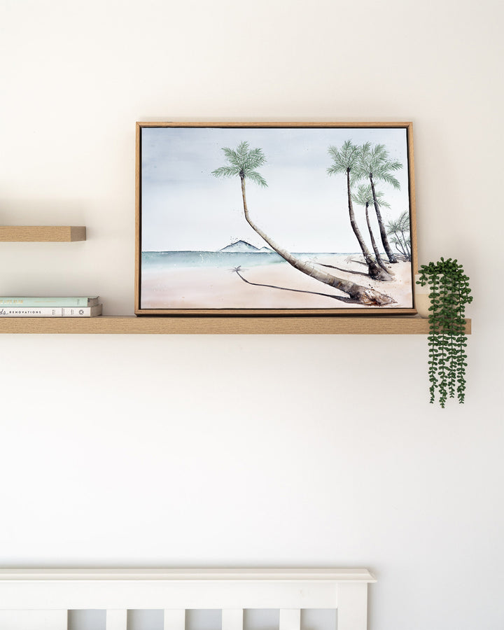 Where The Palm Trees Lead – Port Douglas beach and palm trees, framed canvas in oak float frame, styled on a floating shelf