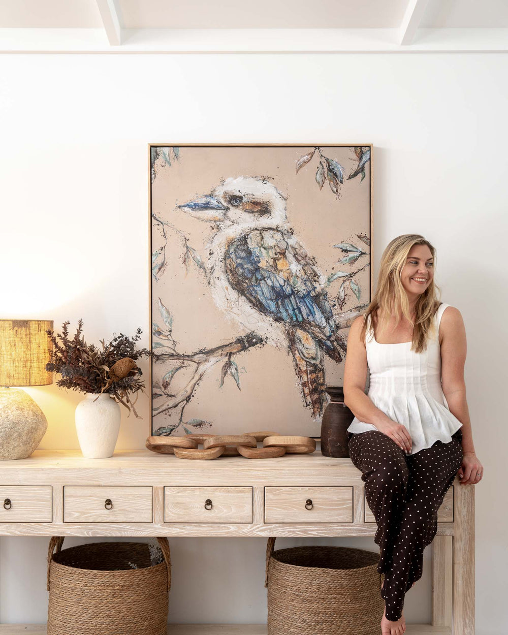 Woman sitting on a console beside Whittaker | Kookaburra Fine Art Print, with artwork and decor in view.