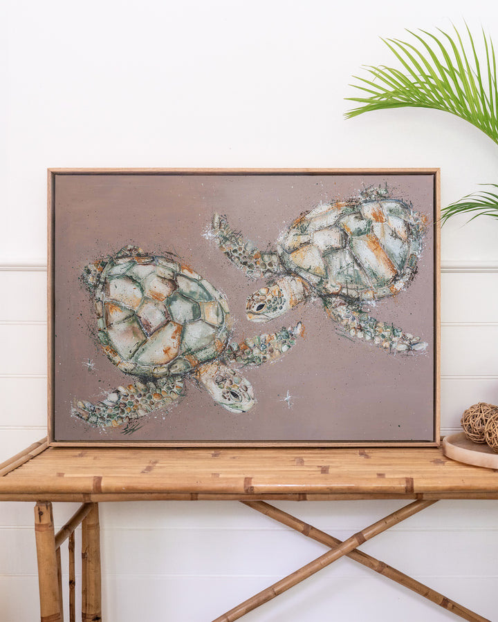 Winter Solstice – green sea turtles, framed canvas in oak float frame, styled on a rattan table