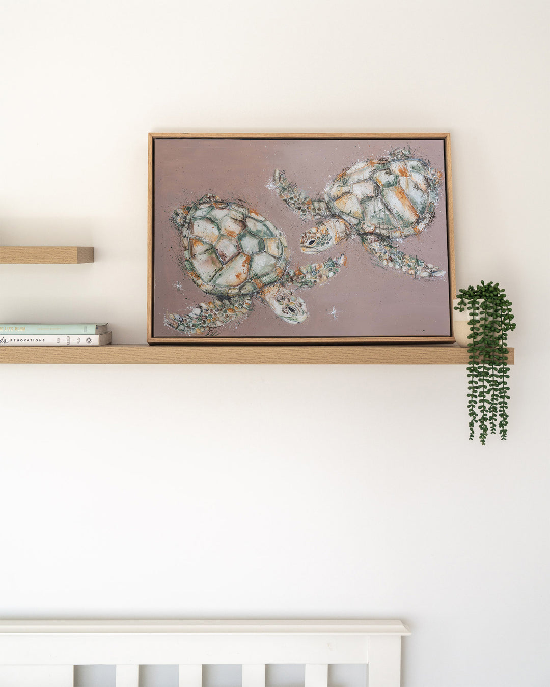 Winter Solstice – green sea turtles, framed canvas in oak float frame, styled on a floating shelf