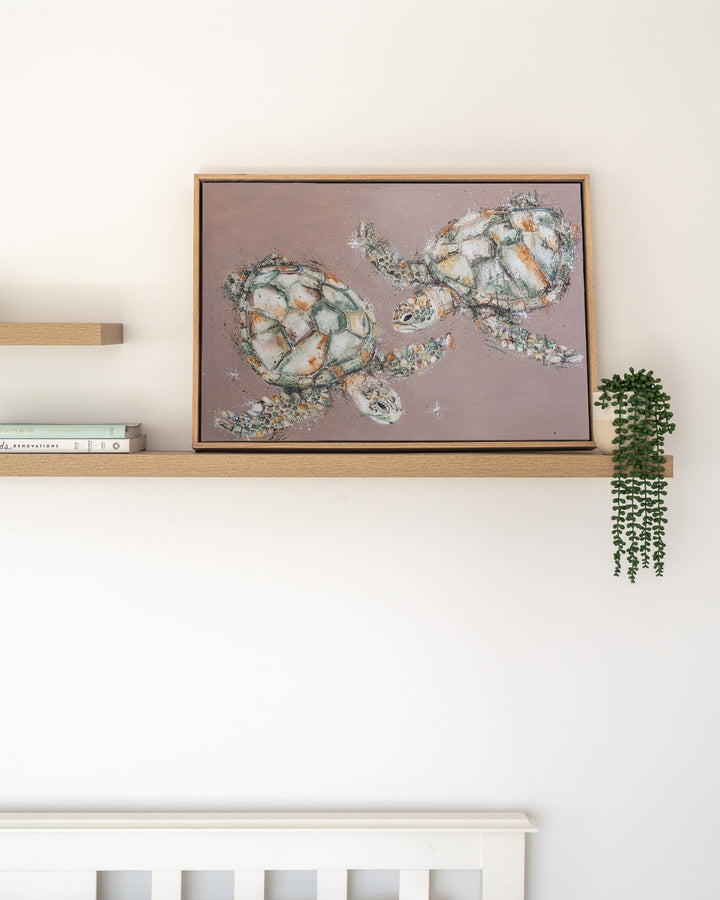 Winter Solstice – green sea turtles, framed canvas in oak float frame, styled on a floating shelf