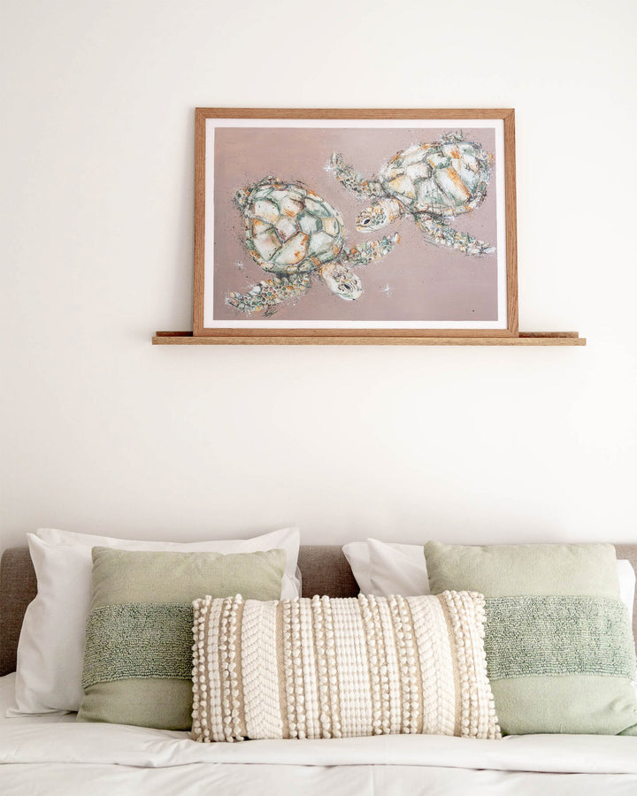 Winter Solstice – green sea turtles, framed paper print in oak frame, styled above a bed