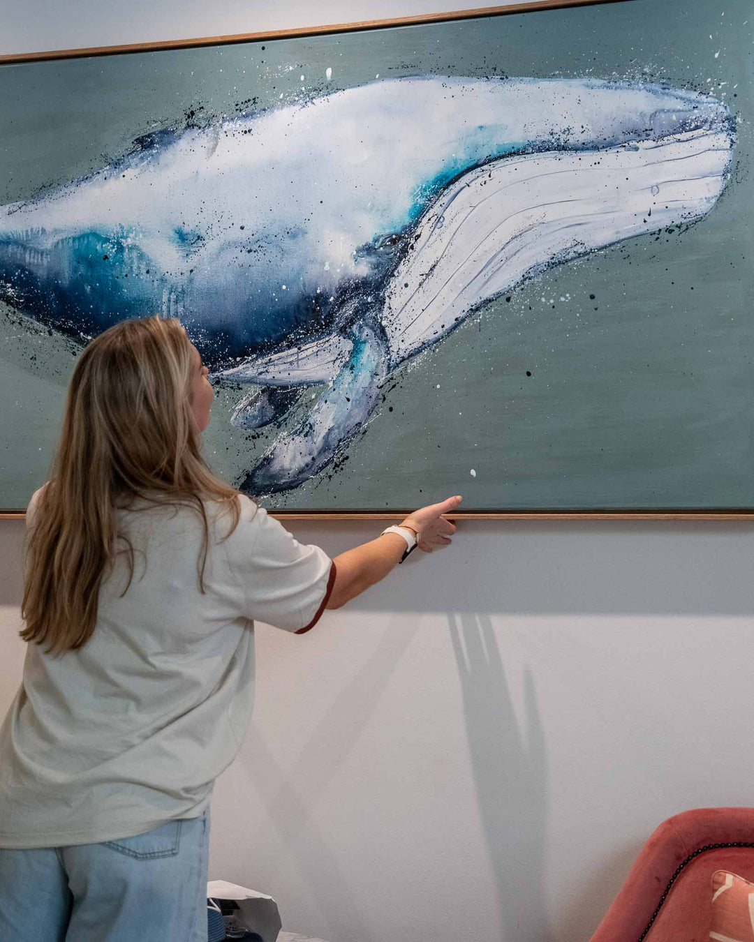 A woman points at the “You’re Gonna Go Far” artwork hanging above a modern couch.